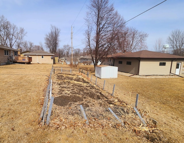 view of yard with a wooden deck, an outbuilding, a shed, and fence