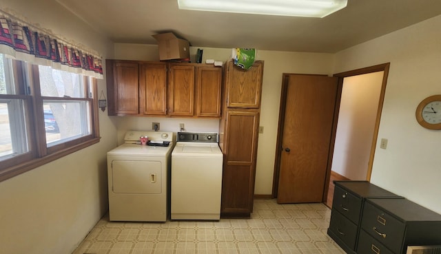 clothes washing area with cabinet space, light floors, and washer and clothes dryer