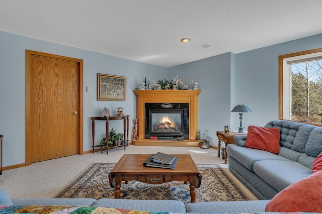 carpeted living area featuring visible vents, a textured ceiling, baseboards, and a glass covered fireplace