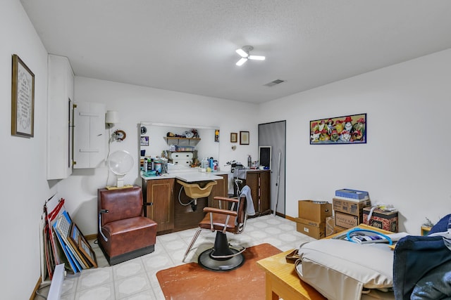 interior space featuring visible vents, light floors, a textured ceiling, and baseboards