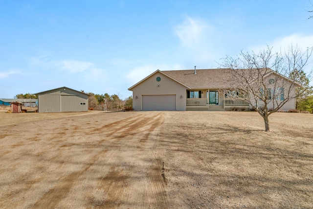 ranch-style home featuring a garage, a porch, and dirt driveway