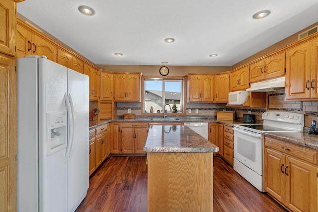 kitchen featuring under cabinet range hood, white appliances, dark wood-style floors, and a sink