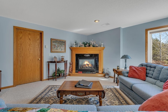 living room featuring visible vents, baseboards, a textured ceiling, carpet floors, and a glass covered fireplace