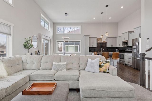 living room featuring recessed lighting, dark wood-type flooring, and a towering ceiling