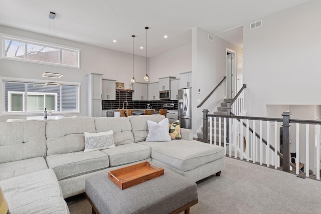 living area with recessed lighting, visible vents, carpet floors, and a high ceiling