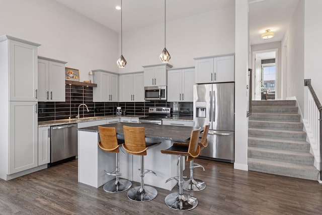 kitchen with dark wood-style floors, decorative backsplash, a breakfast bar area, and stainless steel appliances