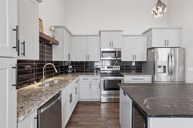 kitchen featuring a sink, dark wood finished floors, decorative backsplash, stainless steel appliances, and open shelves