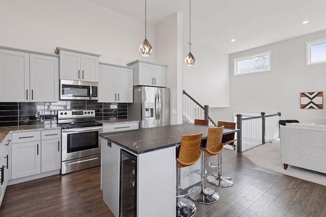 kitchen with wine cooler, dark wood-type flooring, appliances with stainless steel finishes, and a breakfast bar area