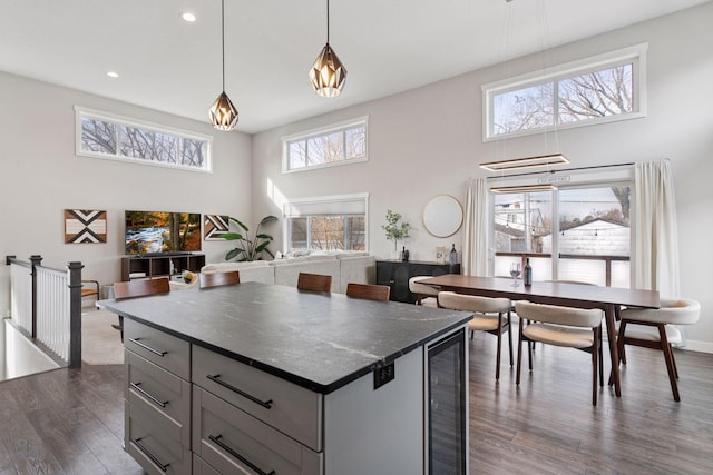 kitchen with dark countertops, wine cooler, a high ceiling, plenty of natural light, and dark wood-style flooring