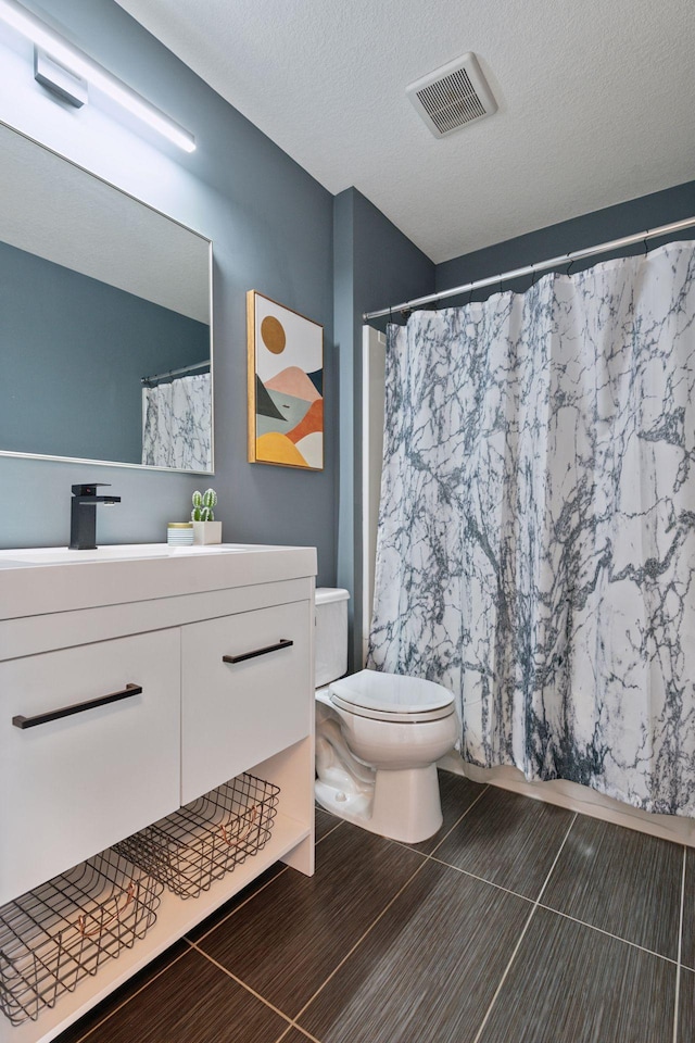 full bathroom featuring visible vents, toilet, vanity, a shower with curtain, and a textured ceiling