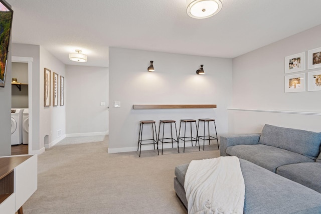 living area featuring carpet floors, baseboards, and separate washer and dryer