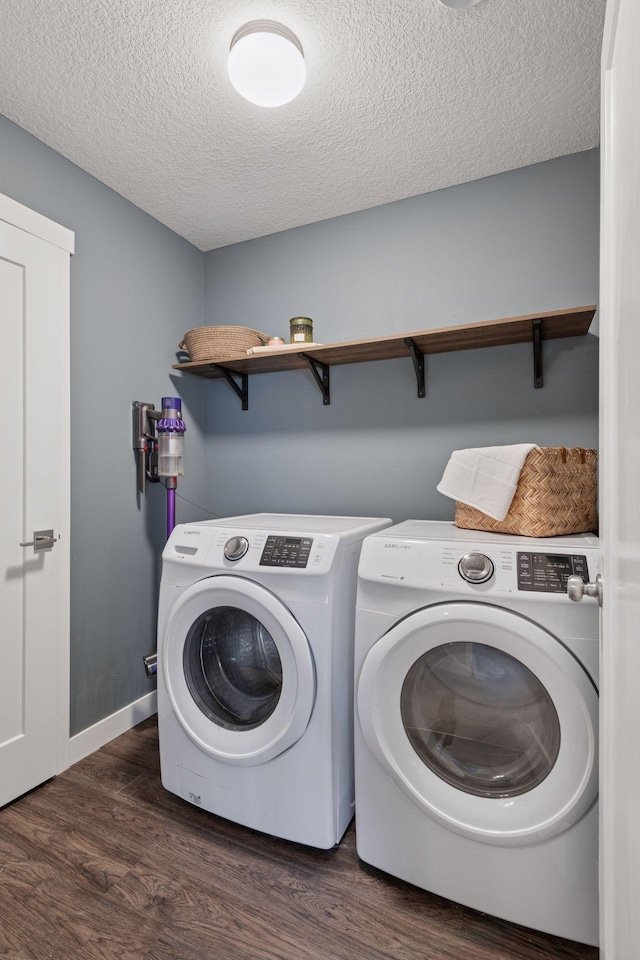 laundry room with wood finished floors, baseboards, washing machine and clothes dryer, laundry area, and a textured ceiling