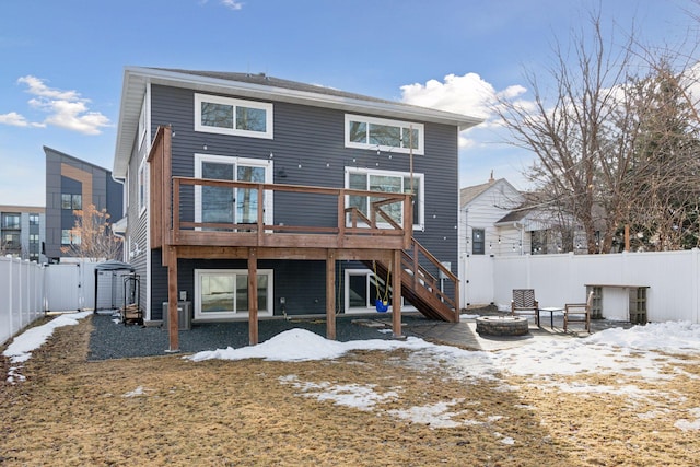 snow covered back of property featuring stairway, a gate, a wooden deck, an outdoor fire pit, and a fenced backyard