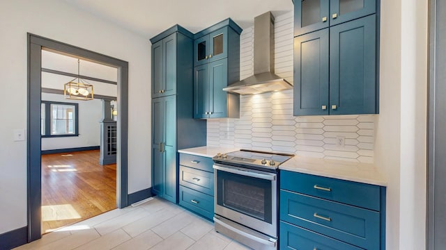 kitchen with light wood-style flooring, stainless steel range with electric cooktop, glass insert cabinets, wall chimney exhaust hood, and backsplash