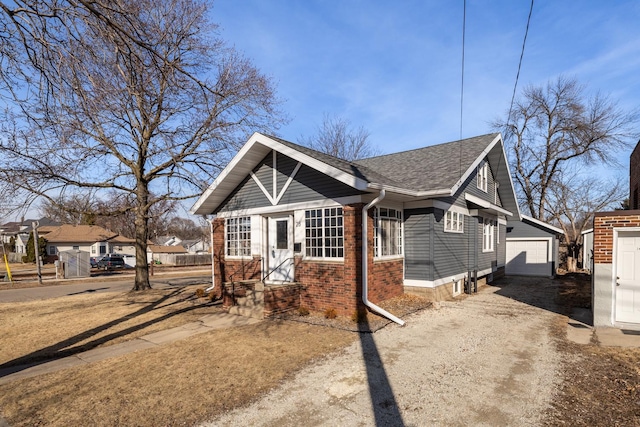 view of front of house featuring a detached garage, an outbuilding, brick siding, and a shingled roof