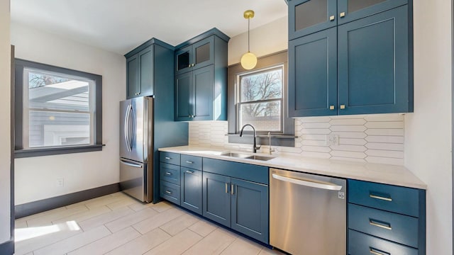 kitchen featuring tasteful backsplash, baseboards, decorative light fixtures, stainless steel appliances, and a sink