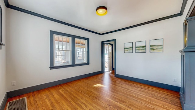 unfurnished room with crown molding, light wood-style flooring, baseboards, and visible vents