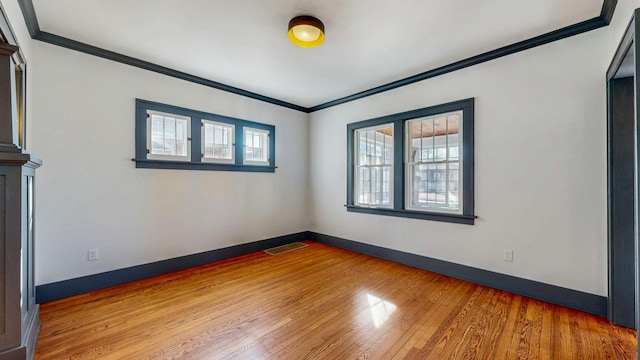 spare room featuring visible vents, wood finished floors, baseboards, and ornamental molding