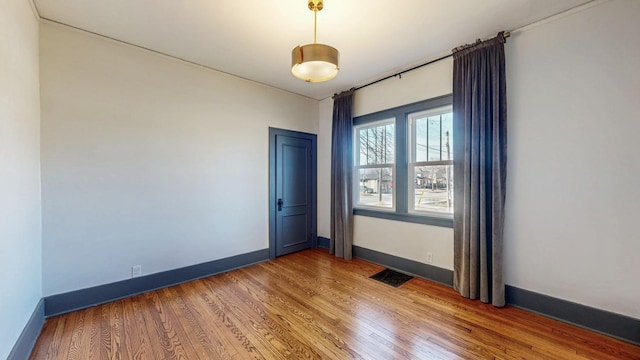 empty room with visible vents, baseboards, and light wood-style floors