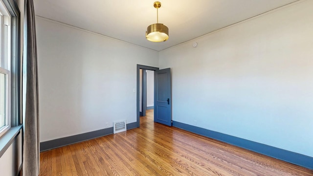 unfurnished room with visible vents, baseboards, and wood finished floors