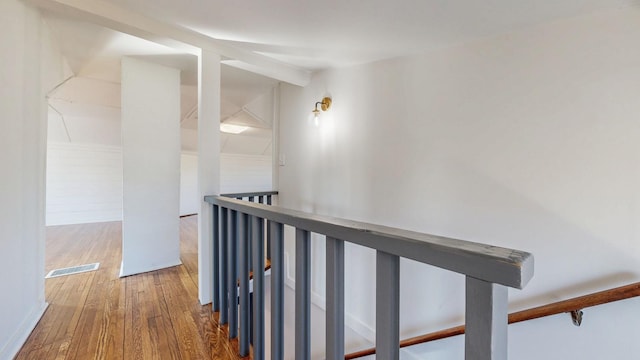 hall with visible vents, an upstairs landing, and hardwood / wood-style floors