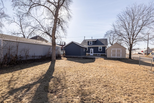 rear view of house with an outbuilding, a storage unit, and fence