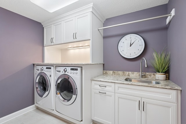 laundry room featuring light tile patterned flooring, cabinet space, a textured ceiling, independent washer and dryer, and a sink