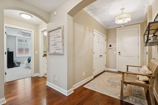 foyer entrance featuring crown molding, dark wood-style floors, arched walkways, and baseboards