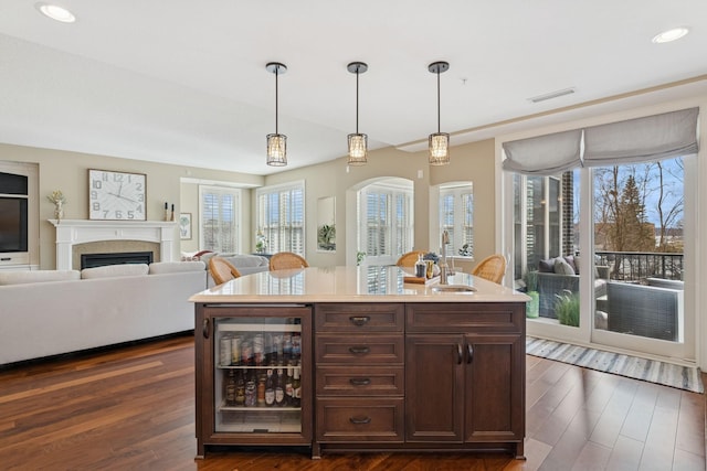 kitchen with visible vents, a sink, wine cooler, a fireplace, and dark wood-style flooring