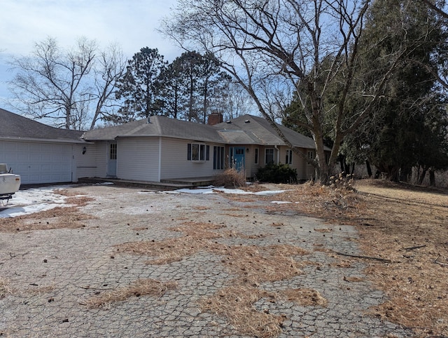 view of front of house featuring an attached garage, a chimney, and driveway