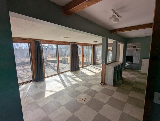 interior space featuring beam ceiling and a brick fireplace