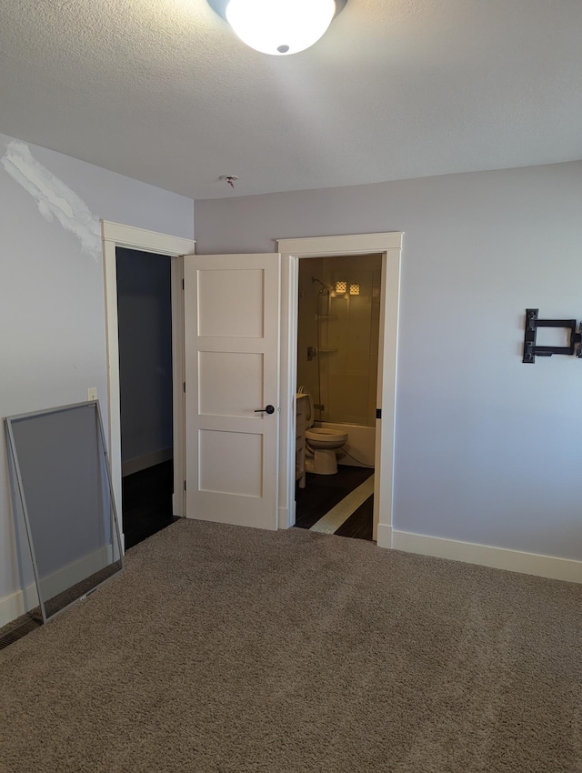 unfurnished bedroom featuring baseboards, carpet, ensuite bathroom, and a textured ceiling