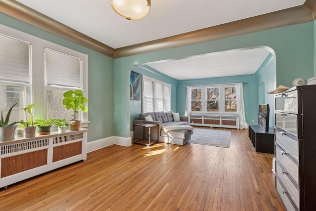 sitting room with hardwood / wood-style flooring, radiator, and arched walkways