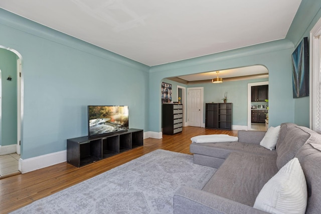 living room with arched walkways, baseboards, and wood finished floors