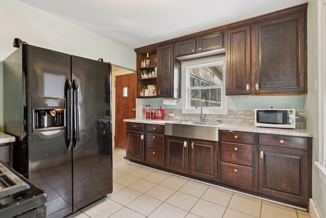 kitchen featuring white microwave, open shelves, a sink, dark brown cabinets, and black fridge with ice dispenser