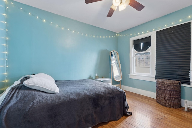 bedroom with ceiling fan, baseboards, and wood finished floors