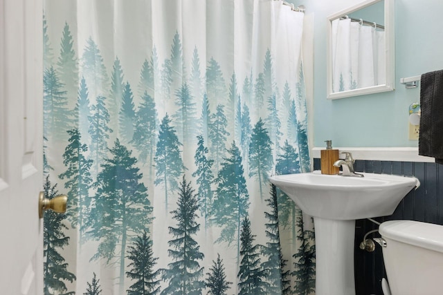 bathroom featuring a wainscoted wall and toilet