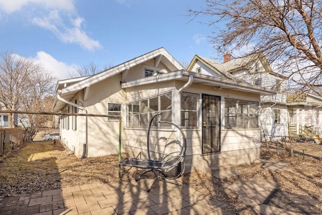 exterior space with stucco siding, fence, a chimney, and a sunroom