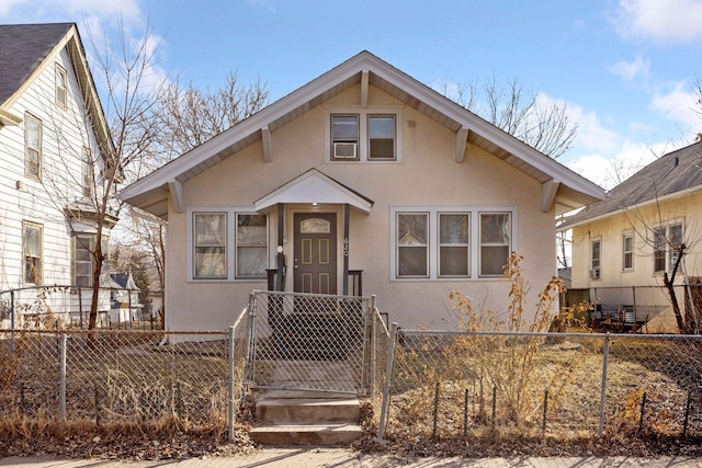 bungalow-style house featuring stucco siding, a fenced front yard, and a gate