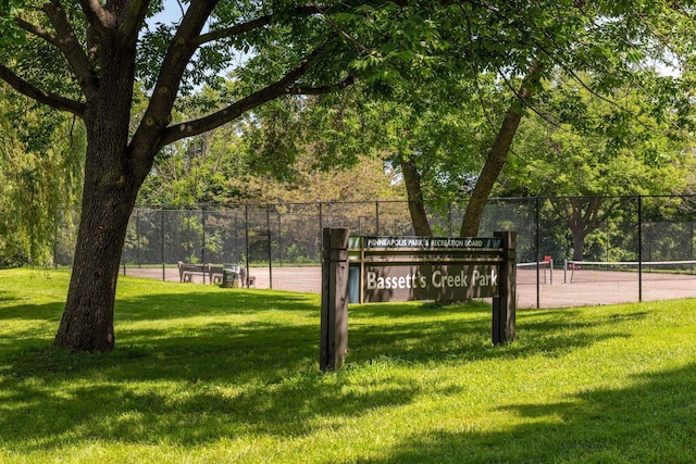 view of home's community with a tennis court, a yard, and fence