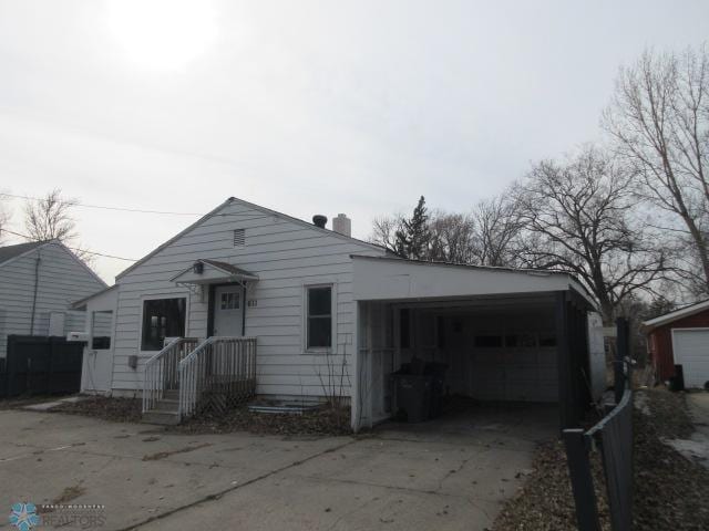 view of front facade featuring an attached garage, a chimney, and driveway