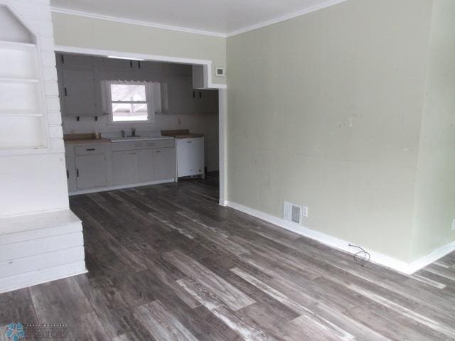 kitchen with visible vents, ornamental molding, a sink, dark wood-style floors, and baseboards