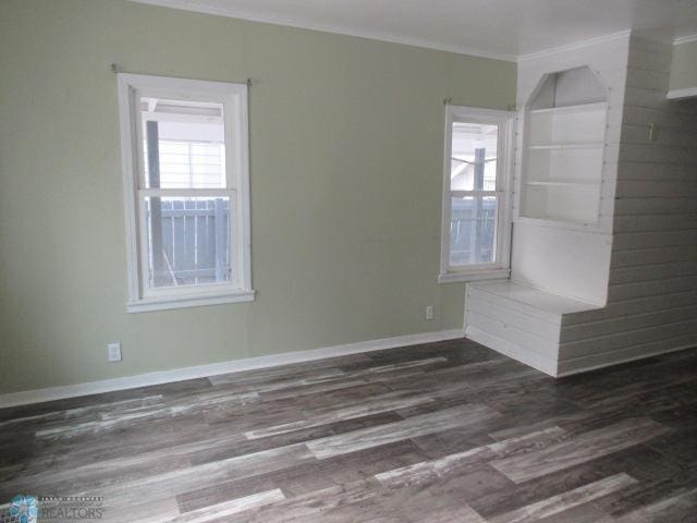 unfurnished room featuring dark wood-style floors, baseboards, and ornamental molding