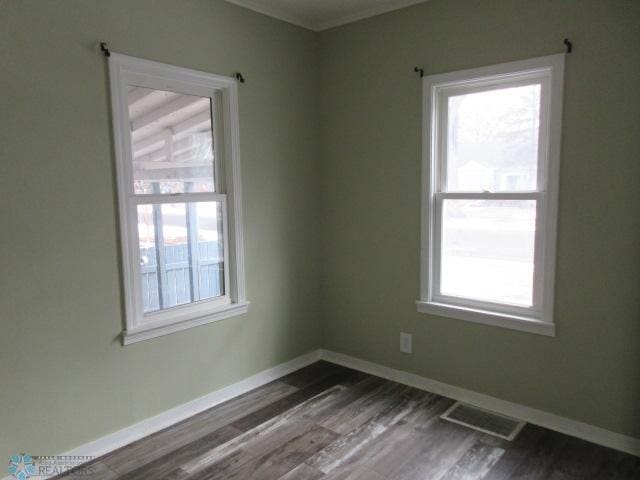 empty room featuring dark wood-type flooring, baseboards, and visible vents