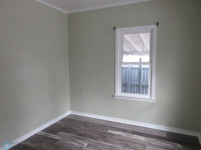 spare room with baseboards, dark wood-style flooring, and crown molding