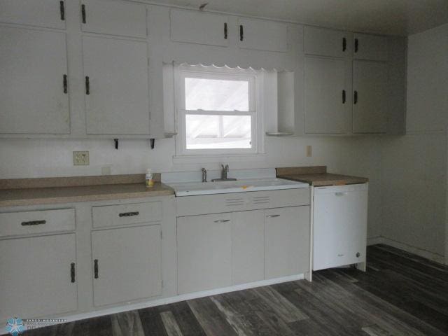 kitchen with white dishwasher, dark wood finished floors, white cabinets, and light countertops