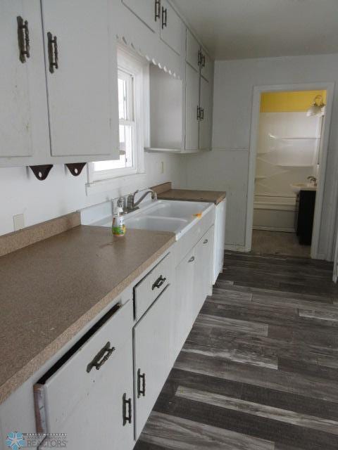 kitchen with dark wood-style flooring, white cabinetry, and a sink