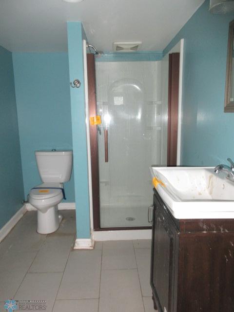 bathroom with tile patterned flooring, a shower stall, vanity, and toilet