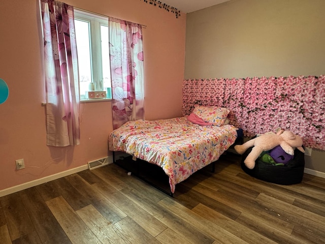 bedroom with wood finished floors, visible vents, and baseboards