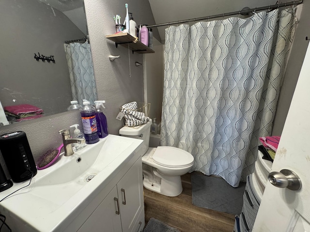 full bath with toilet, a shower with shower curtain, wood finished floors, a textured wall, and vanity